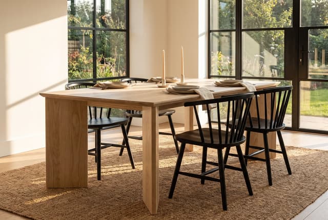 The Kouper Dining Table in a modern farmhouse dining room, steel windows onto the garden, the table set for dinner
