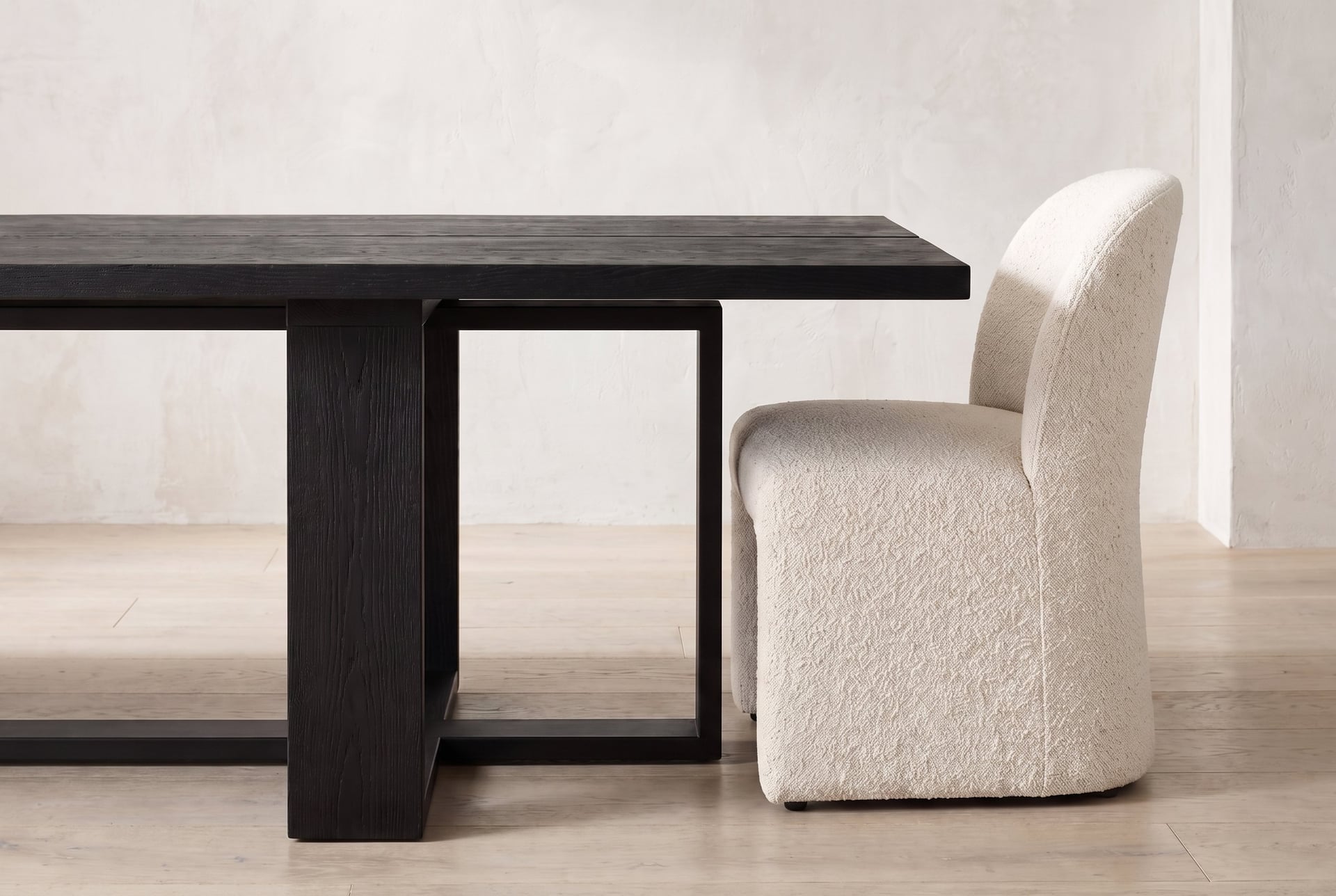 Tesseract Dining Table in black oak, a chair pulled up at the end, sliding under the overhang