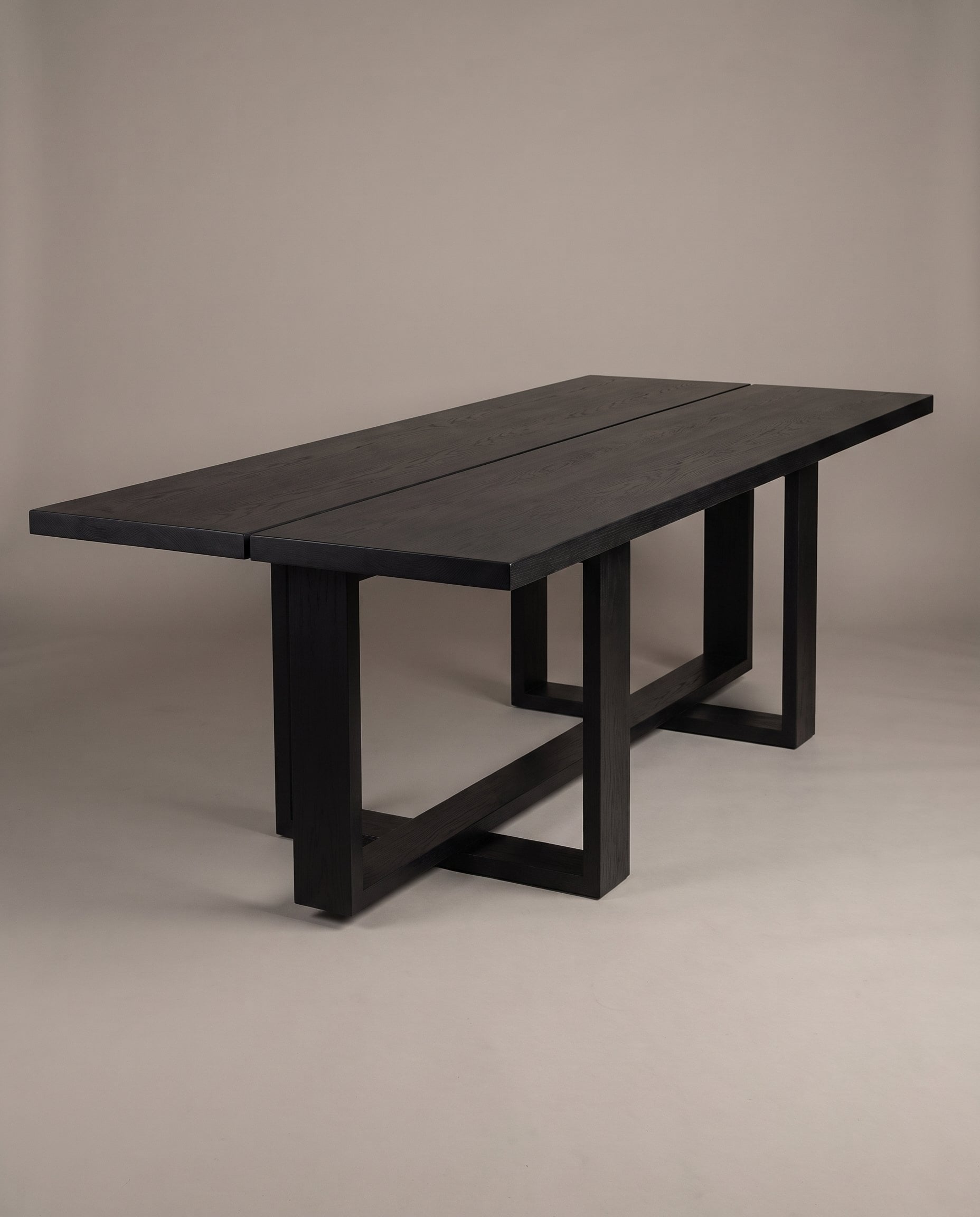 Tesseract Dining Table in black oak, studio portrait on grey, the table alone