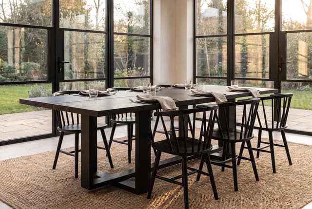 The Tesseract Dining Table in a modern farmhouse dining room, steel windows onto the garden, laid for dinner