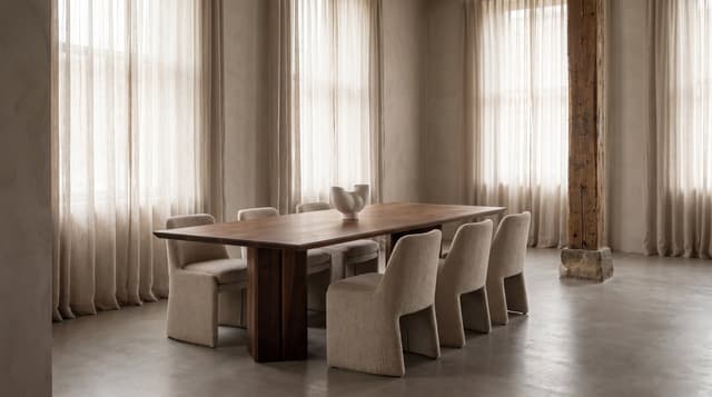 The Vekt Walnut Dining Table in a limewashed loft, linen curtains and boucle chairs, a reclaimed timber post