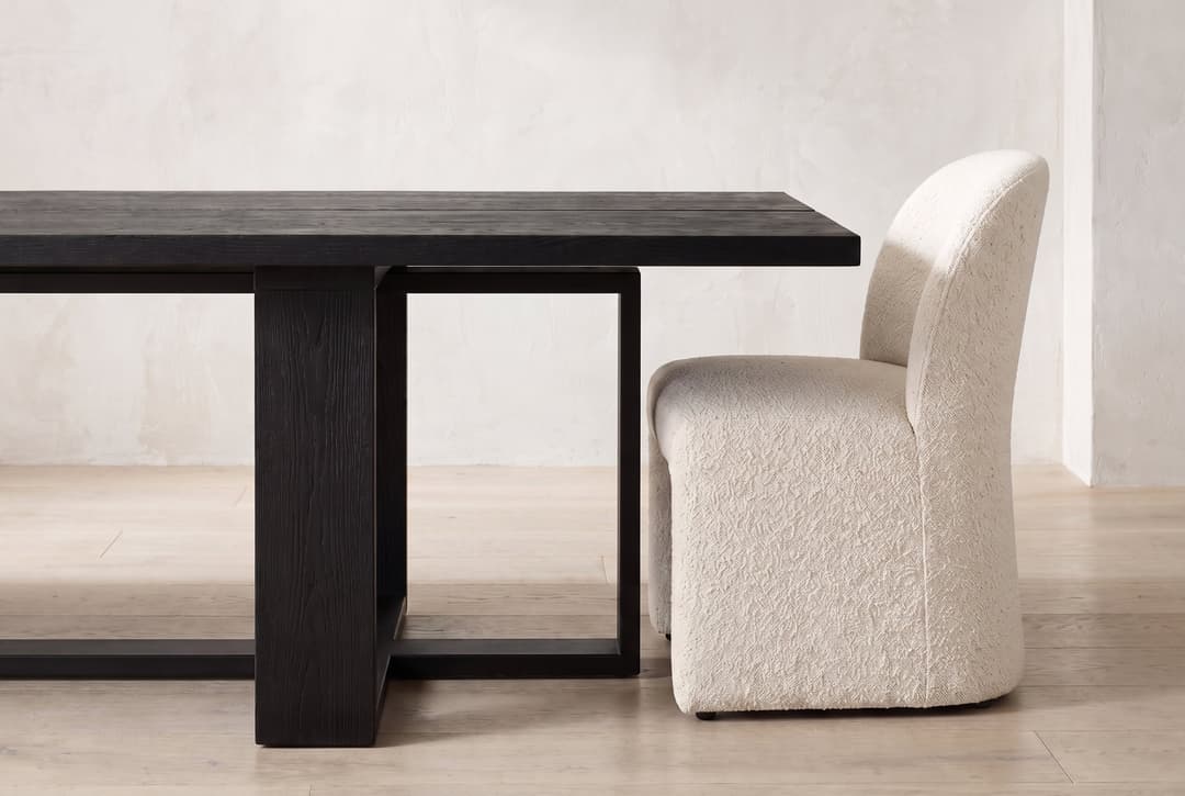 Tesseract Dining Table in black oak, a chair pulled up at the end, sliding under the overhang
