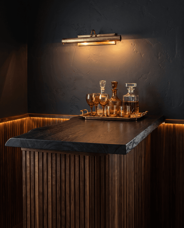 Live-edge black oak bar top in a moody home cocktail bar