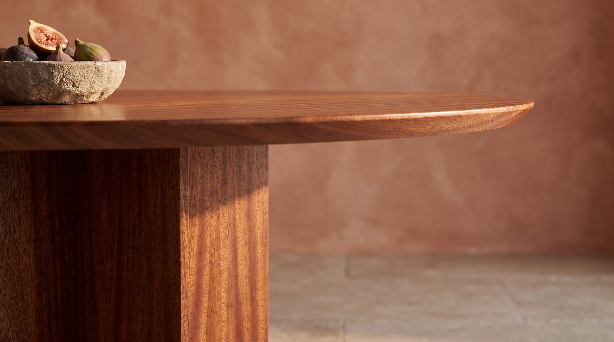 Solid mahogany dining table, face grain — the Kouper Round Dining Table in the beveled rim and a blade, figs in a stone bowl, terracotta plaster