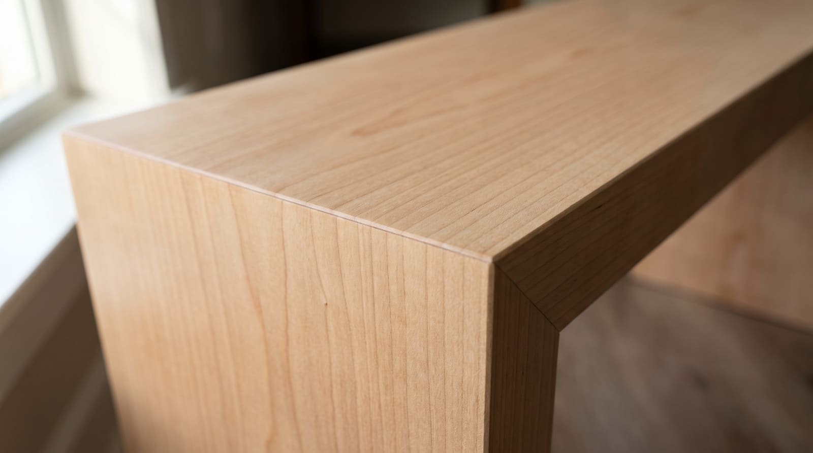 Solid maple tabletop, face grain — looking down a maple waterfall bench at its folded end